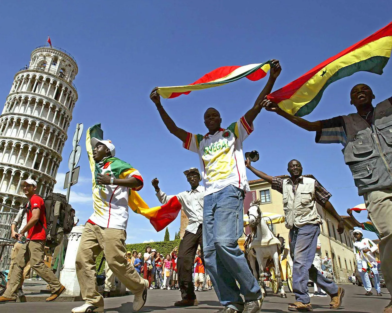 Senegal fans wave their national flags as they celebrate in front of Pisa's leaning tower in Italy