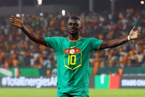 Sadio Mané, the Senegal forward wearing No 10, celebrates scoring a goal for his country at the Africa Cup of Nations by standing before the fans with his arms spread wide.