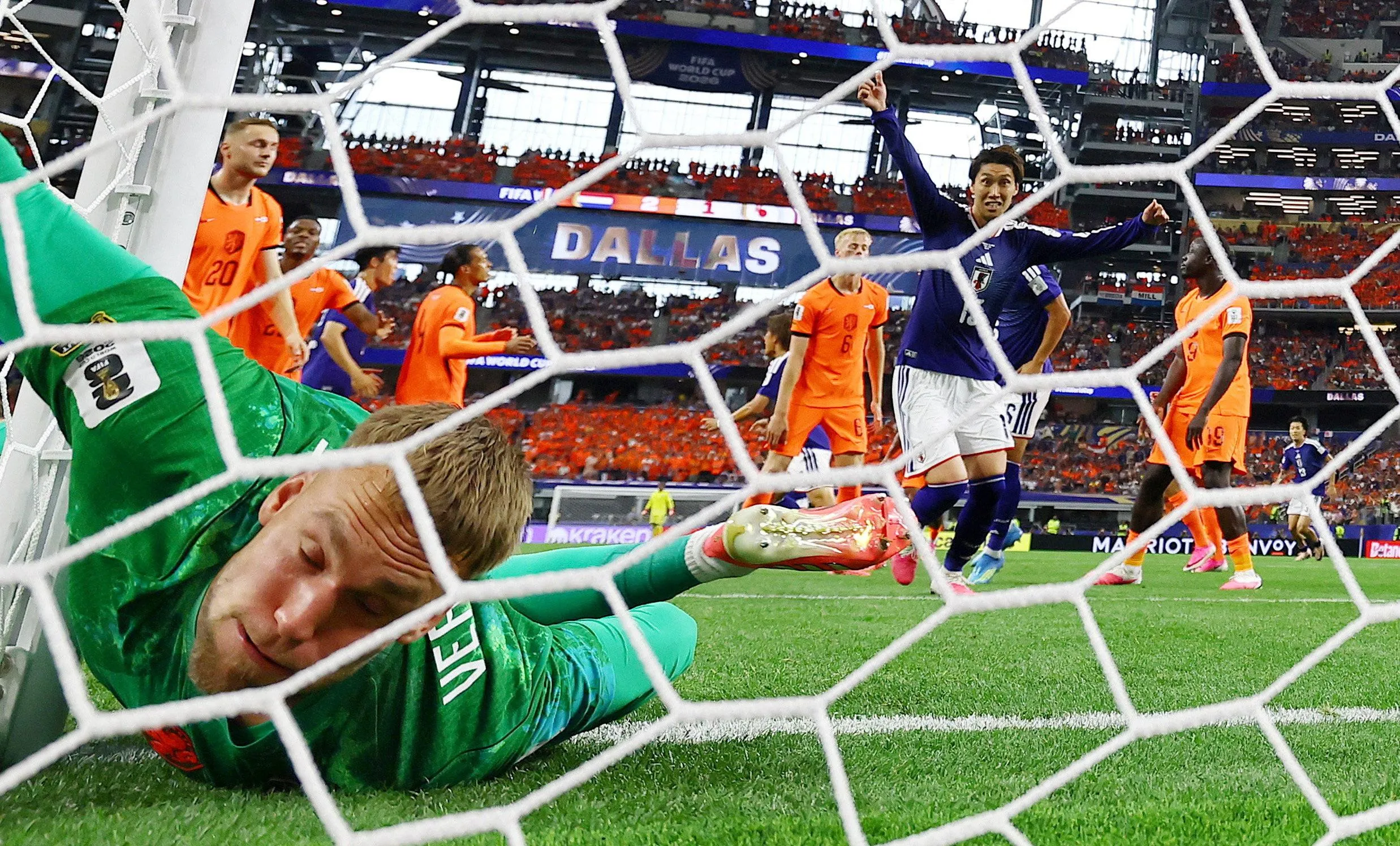 Bert Verbruggen lies in the net as Japan players celebrate their equaliser