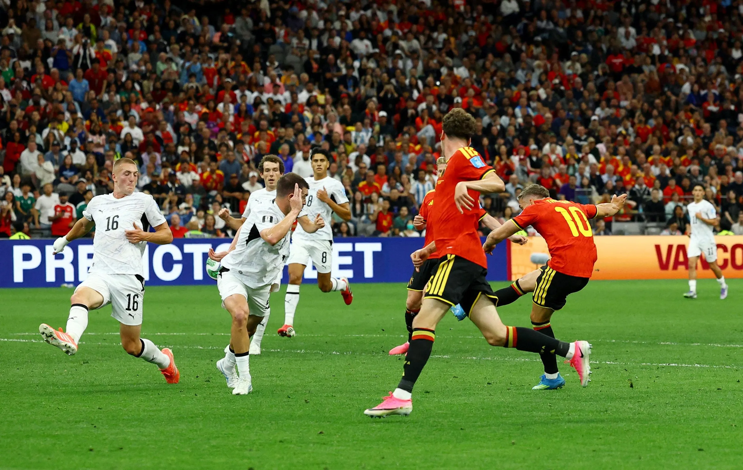 Leandro Trossard shoots before the ball hits the arm of New Zealand's Finn Surman. 