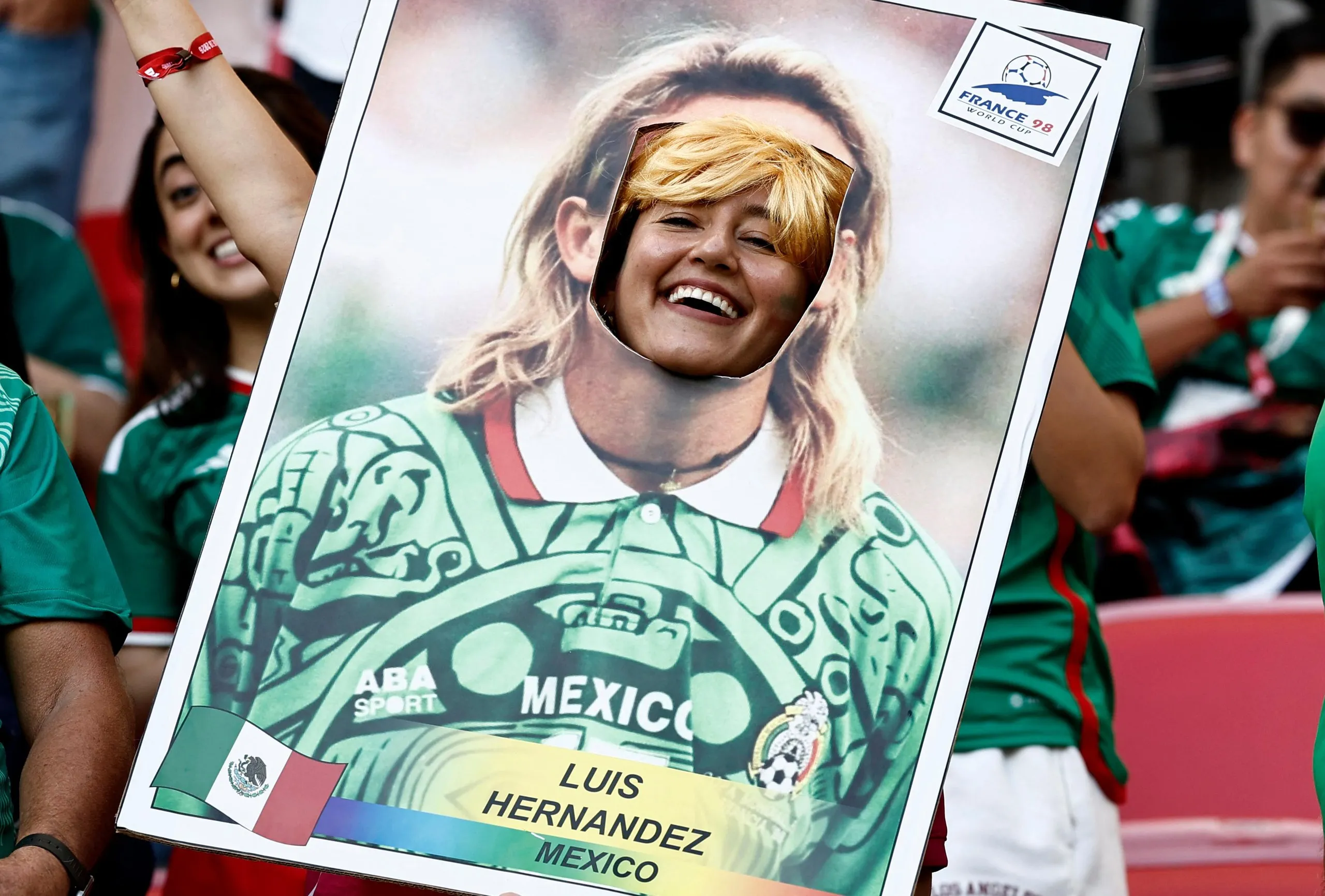 A Mexican fan smiles as she poses for a picture on a cardboard frame depicting former Mexican football player Luis Hernandez