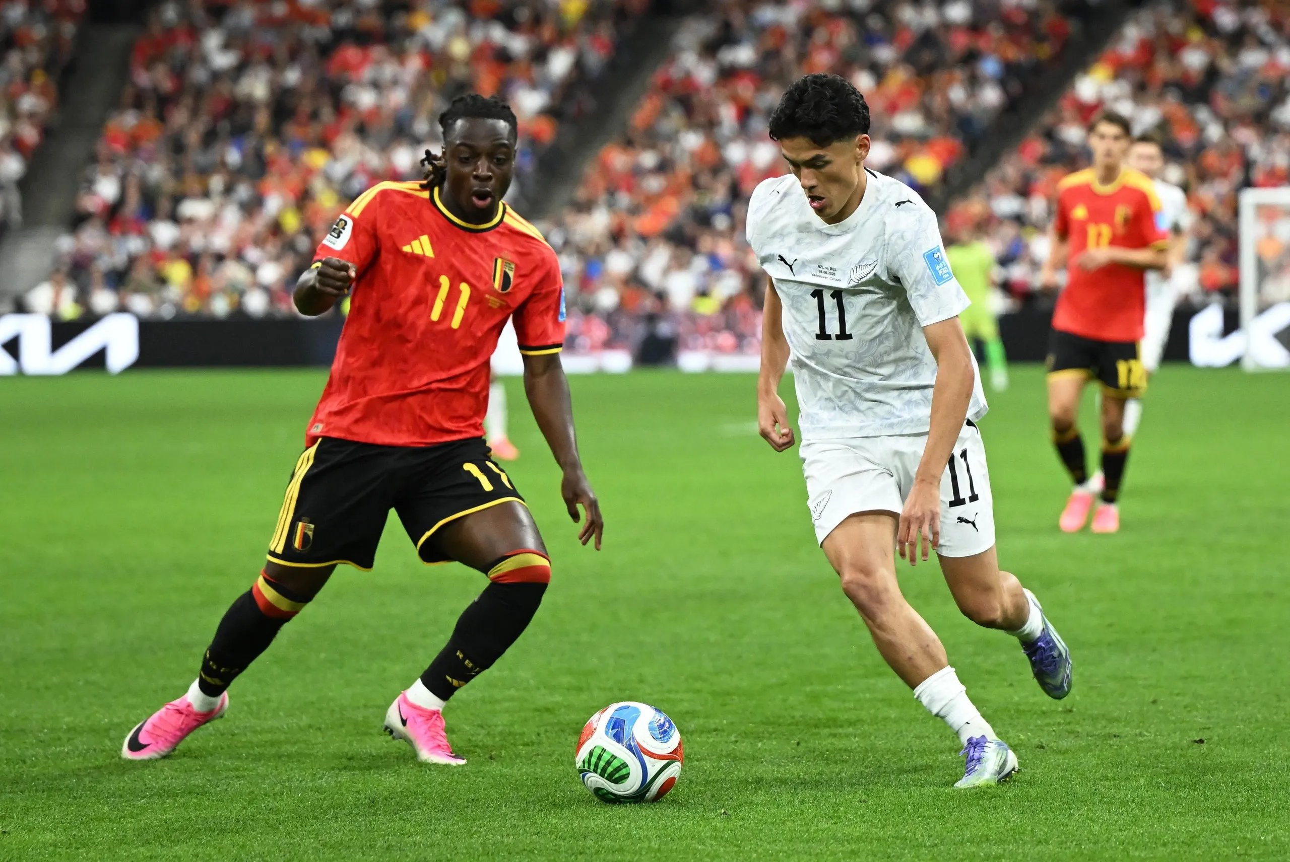 Jeremy Doku comes up against New Zealand's Elijah Just.