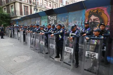 Police officers stand guard near the Zocalo fan zone, where dissident teachers have set up an encampment to demand higher wages and pensions