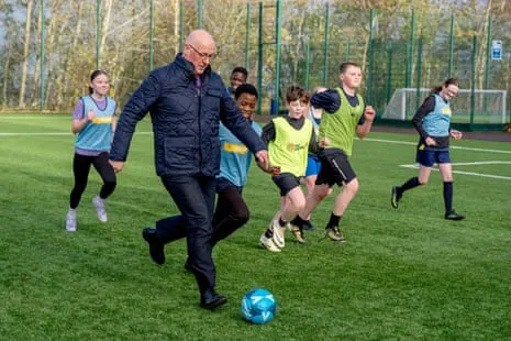 Scottish first minister John Swinney playing football with some children
