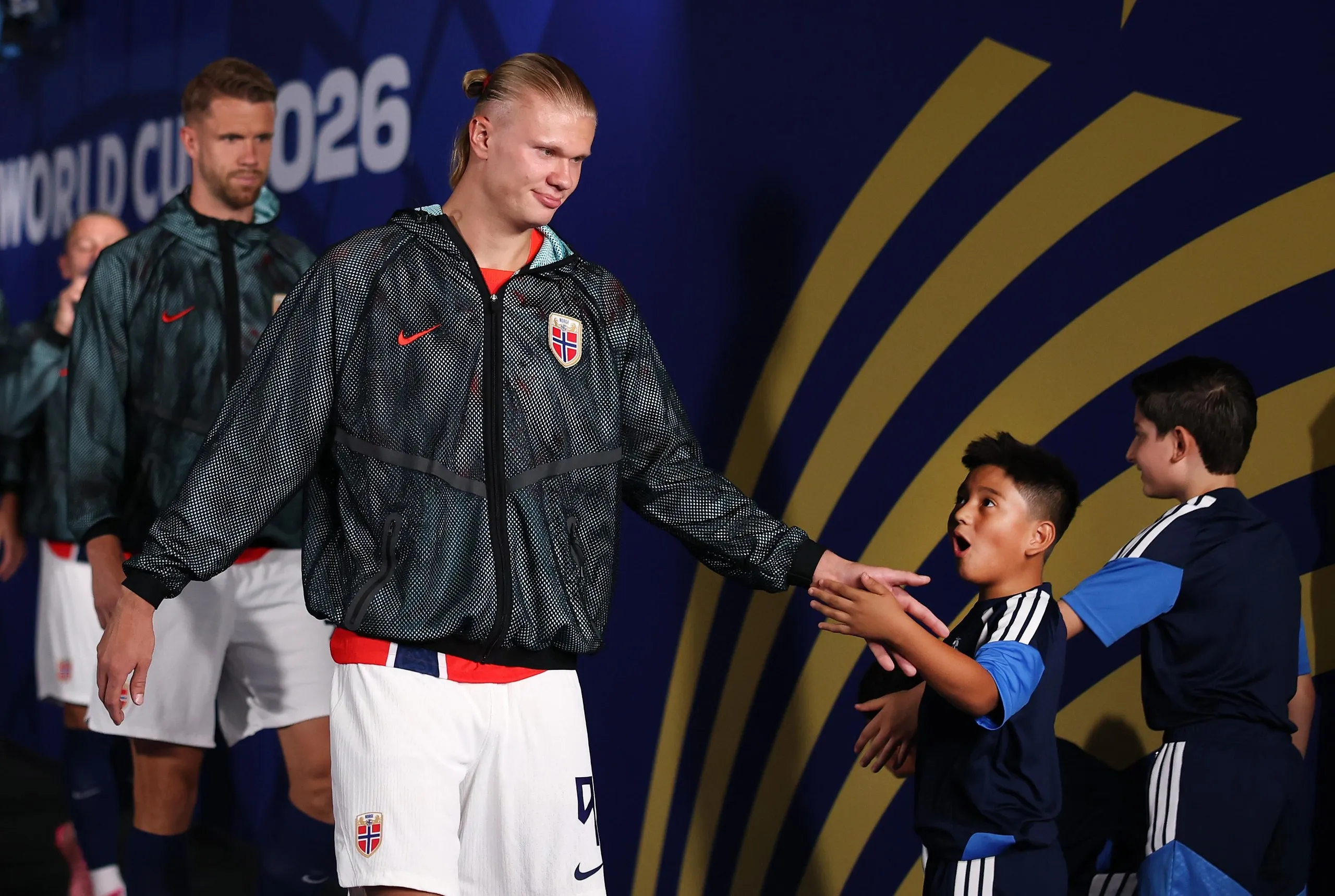 Erling Haaland of Norway high fives one of the World Cup walkout mascots ahead of the last-16 match against Brazil.
