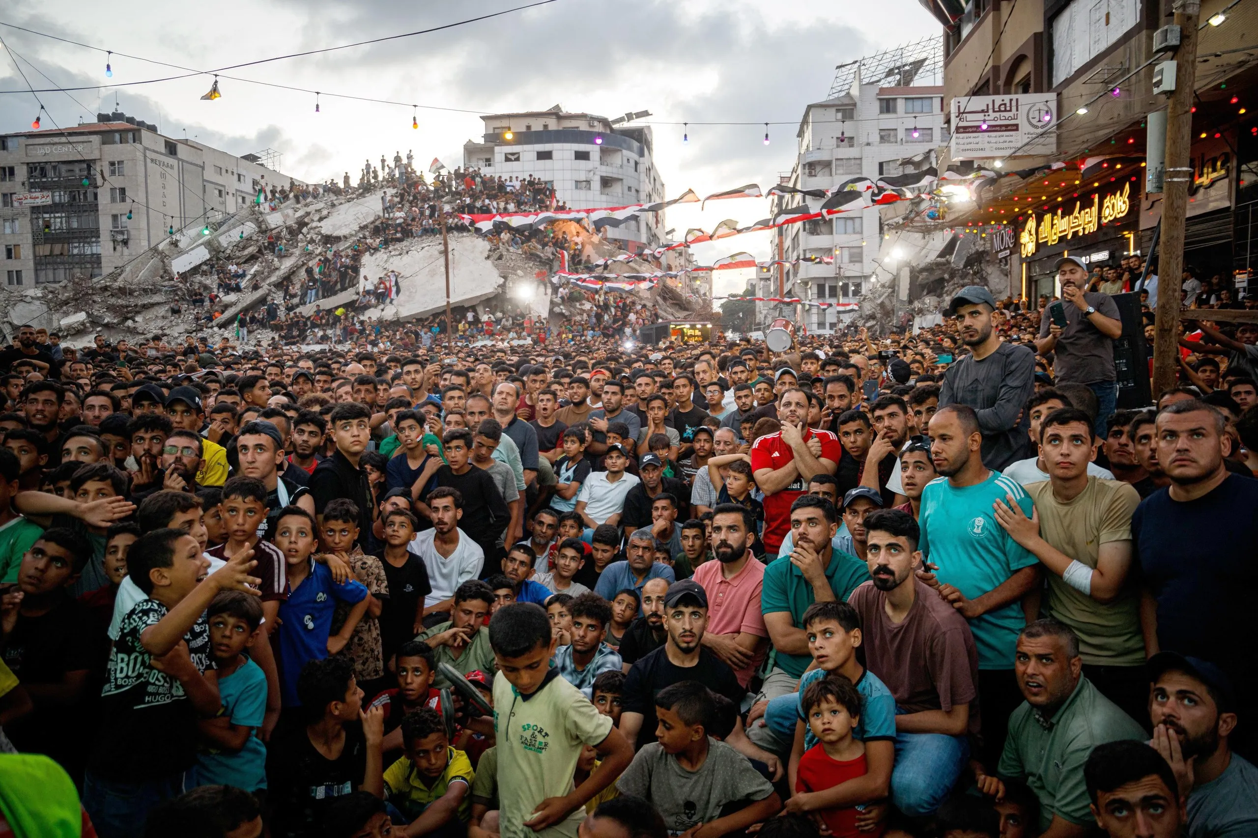 Palestinian football fans gather among war-damaged buildings in Gaza City to watch the match between Argentina and Egypt on a giant outdoor screen.